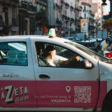 A vibrant Valencia street featuring a taxi and bustling city life.
