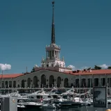 Charming view of the Sochi Marina with yachts and iconic tower on a sunny day.