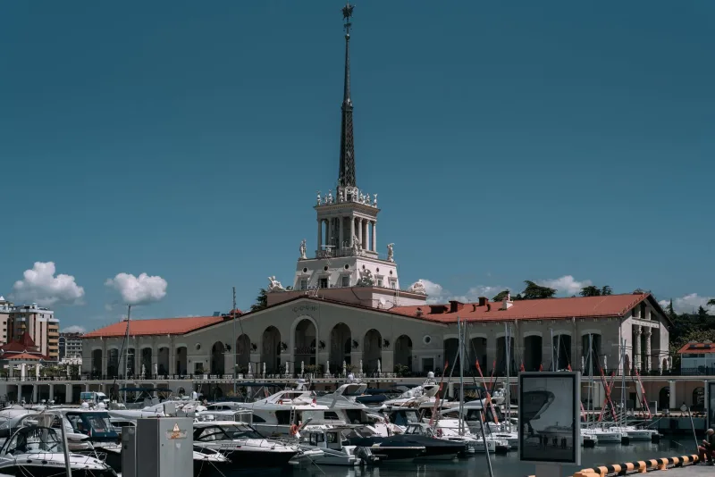Charming view of the Sochi Marina with yachts and iconic tower on a sunny day.