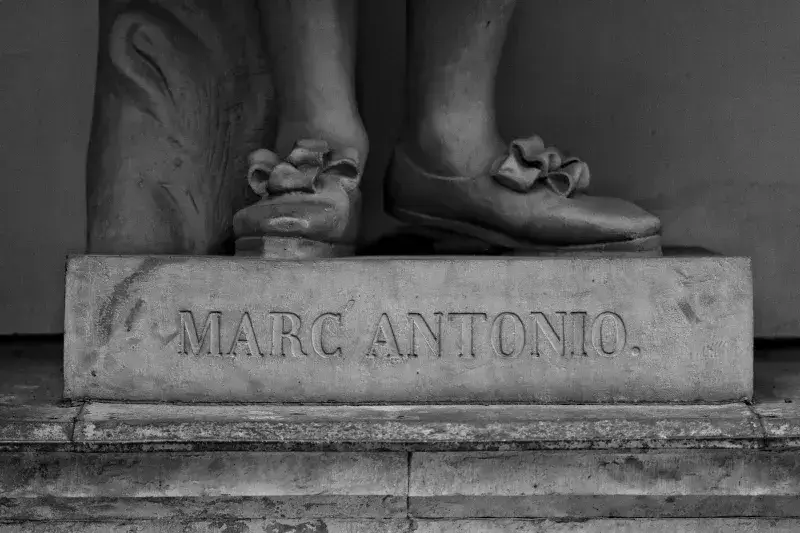 Detailed black and white close-up of a sculpture's base featuring Marc Antonio text.