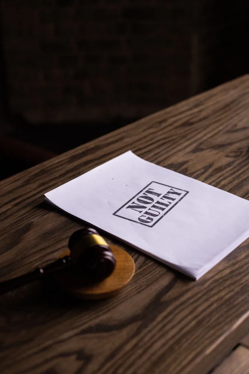 Un martillo judicial junto a un documento de «No culpable» sobre una mesa de madera, simbolizando la justicia.