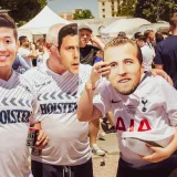 Grupo de aficionados al fútbol que llevan camisetas de su equipo y máscaras en un evento al aire libre en Madrid.