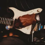 A detailed shot of a musician's hand playing an electric guitar in a New York City setting.