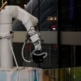 Un brazo robótico blanco en funcionamiento en interiores, con un diseño moderno y tecnología avanzada.