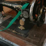 Close-up of a vintage Singer sewing machine with a green measuring tape, evoking nostalgia and craftsmanship.