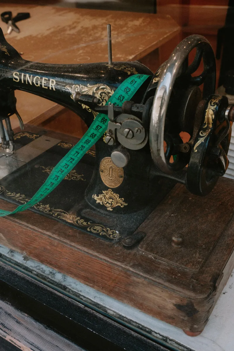 Close-up of a vintage Singer sewing machine with a green measuring tape, evoking nostalgia and craftsmanship.