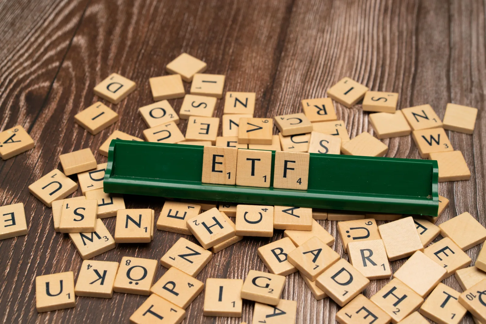 Fichas de madera que deletrean ETF en un soporte de juego, en representación de temas de inversión.