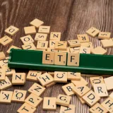 Fichas de madera que deletrean ETF en un soporte de juego, en representación de temas de inversión.