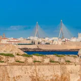 Beautiful view of Cádiz, Spain featuring historic architecture and Puente de la Constitución bridge over the bay.