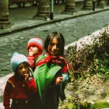 Tres niños con ropa tradicional en una calle empedrada de Ecuador.
