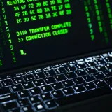 Primer plano de la pantalla de una computadora portátil que muestra texto de código verde. Ideal para temas de ciberseguridad.