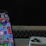 Primer plano de un teléfono inteligente y una computadora portátil sobre un escritorio, que muestran productividad y conectividad.