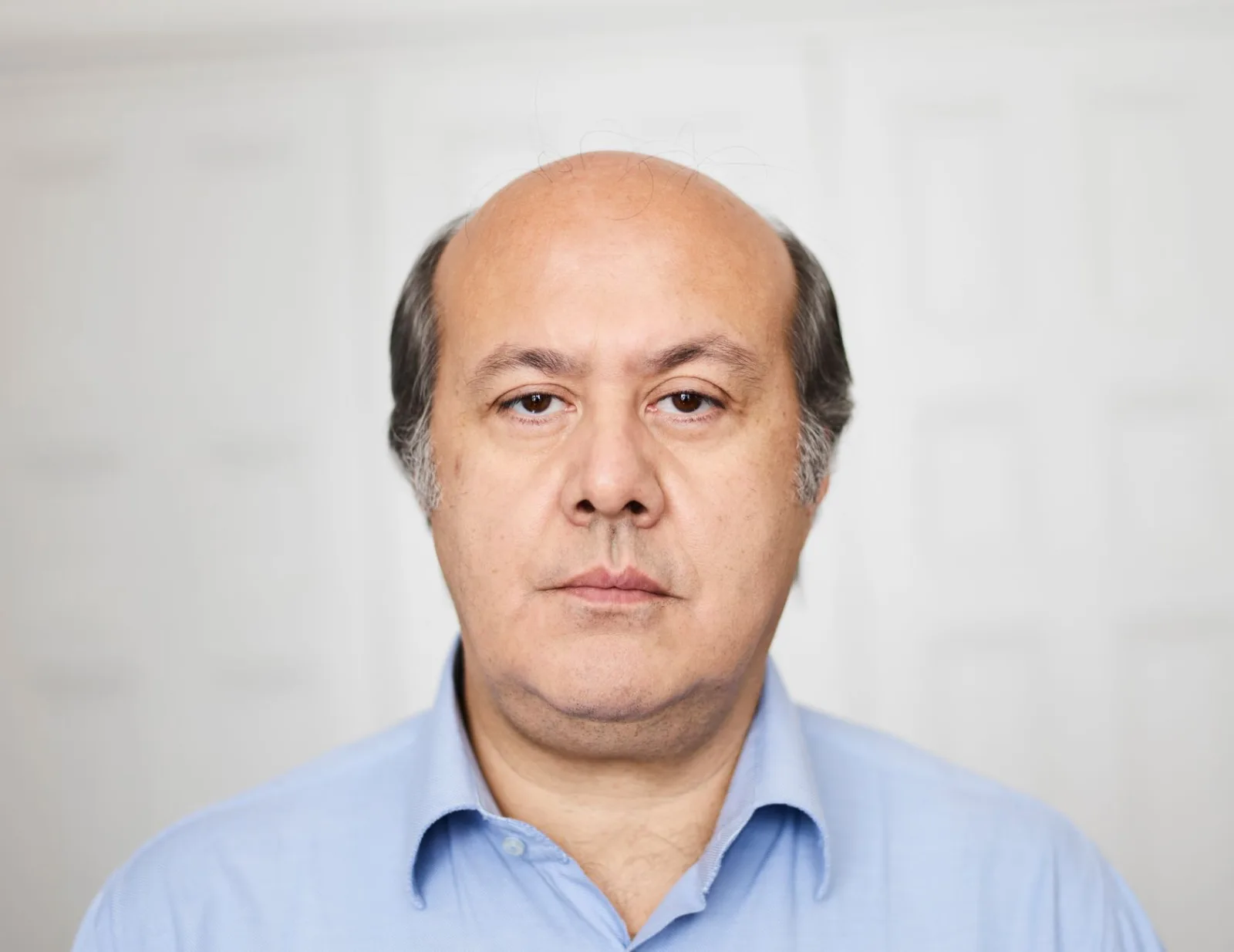 Retrato de estudio de un hombre de mediana edad con expresión neutra.