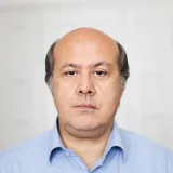 Retrato de estudio de un hombre de mediana edad con expresión neutra.