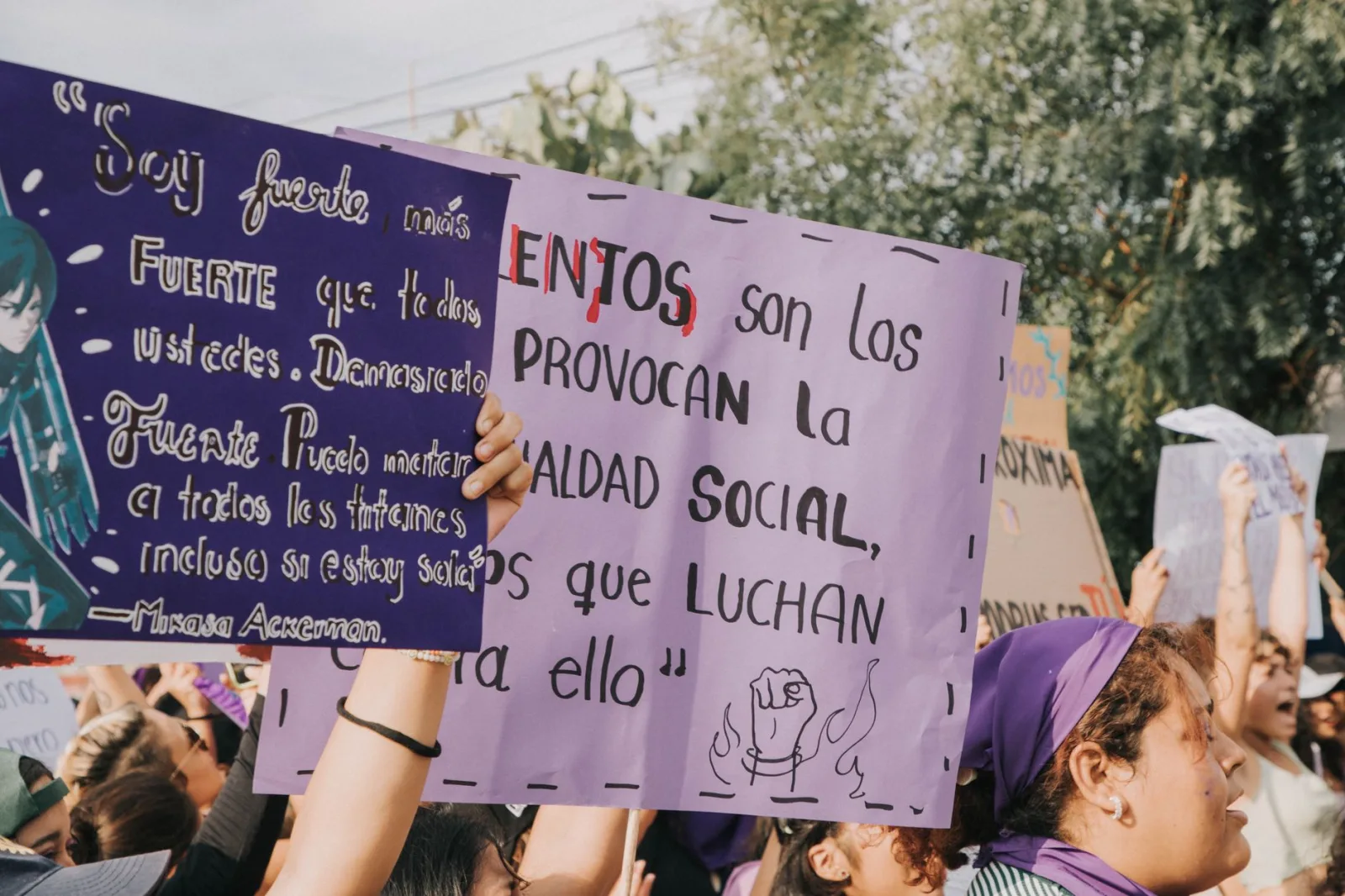 Mujeres sosteniendo carteles de protesta durante una manifestación por la justicia social al aire libre.