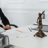 Espacio de trabajo de un profesional legal con una estatua de la Justicia, documentos y un portátil.