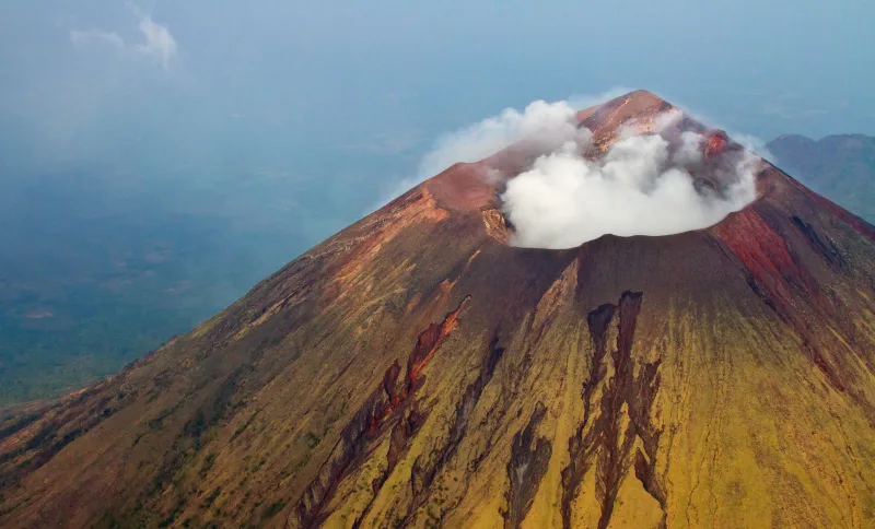 Stunning aerial view of San Cristobal Volcano in Nicaragua with smoke and steam rising from the crater.