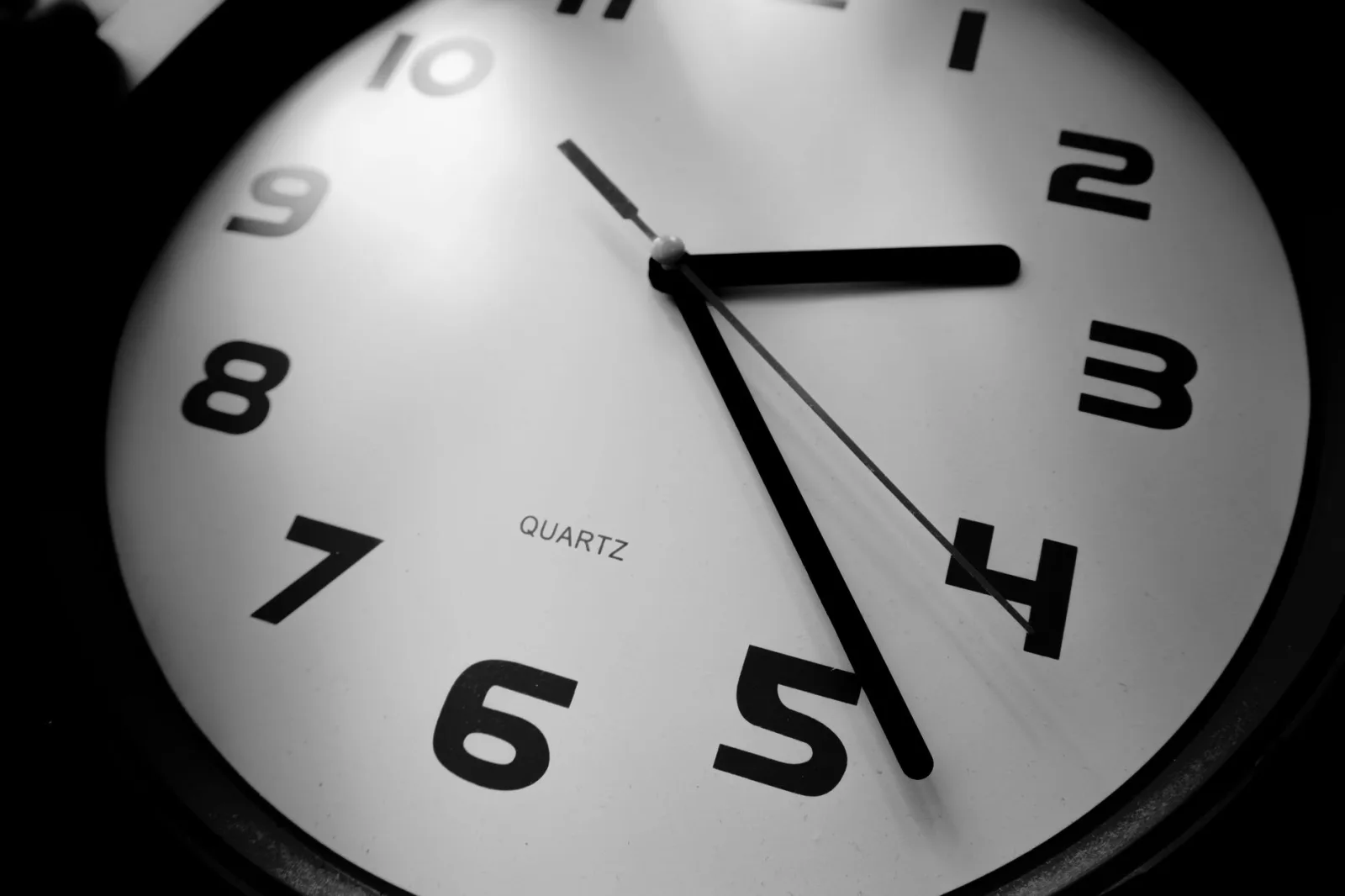 Primer plano en blanco y negro de un reloj de cuarzo que resalta los números y la precisión del tiempo.