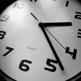 Primer plano en blanco y negro de un reloj de cuarzo que resalta los números y la precisión del tiempo.