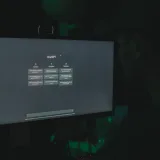 Una persona interactúa con la interfaz de ChatGPT en la pantalla de una computadora, en una habitación con poca iluminación.
