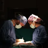 Cirujanos concentrados operando bajo una iluminación dramática en un quirófano de hospital.