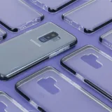 Close-up of a Samsung phone surrounded by transparent cases on a purple surface, showcasing modern technology.