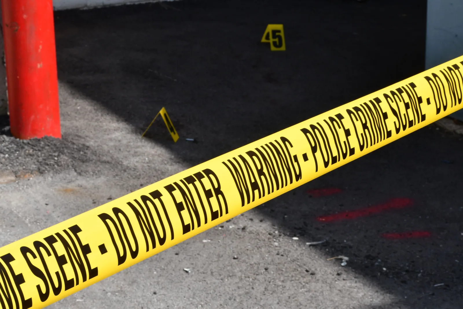 Cinta amarilla policial de escena del crimen que delimita una zona urbana restringida sobre el suelo de concreto.