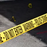 Cinta amarilla policial de escena del crimen que delimita una zona urbana restringida sobre el suelo de concreto.