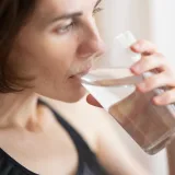 Close-up of an adult woman drinking a glass of water for hydration and health.