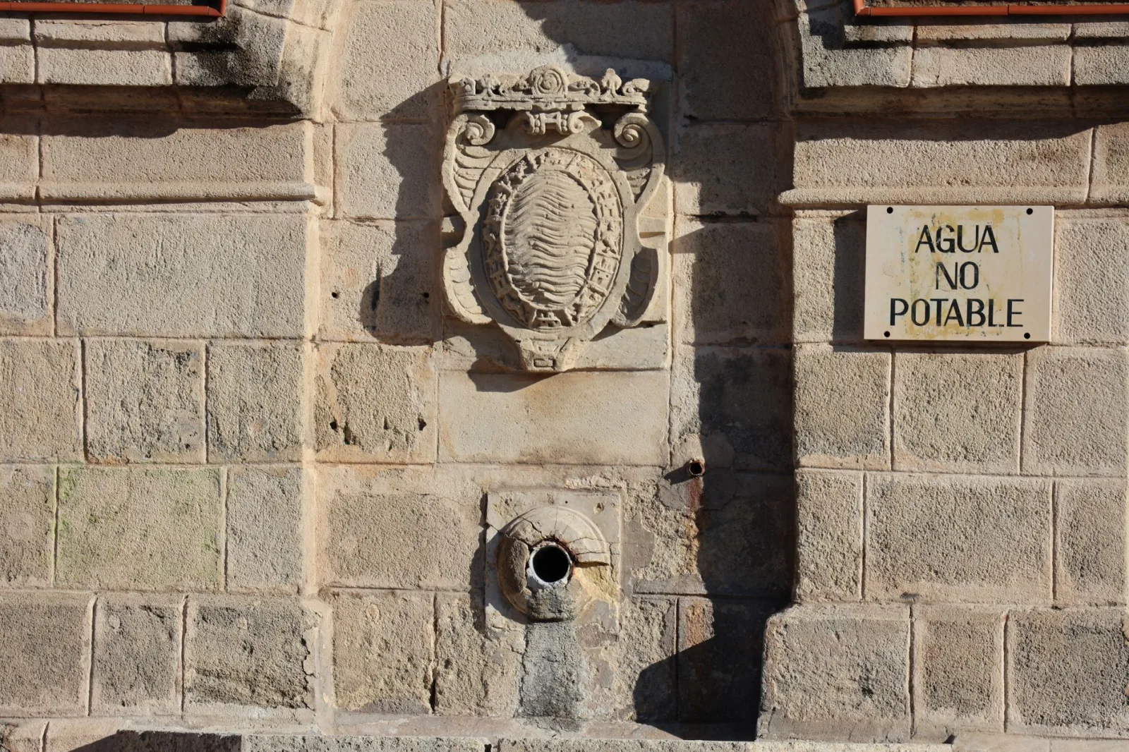 Old stone fountain in Jerez de la Frontera with non-potable water sign.