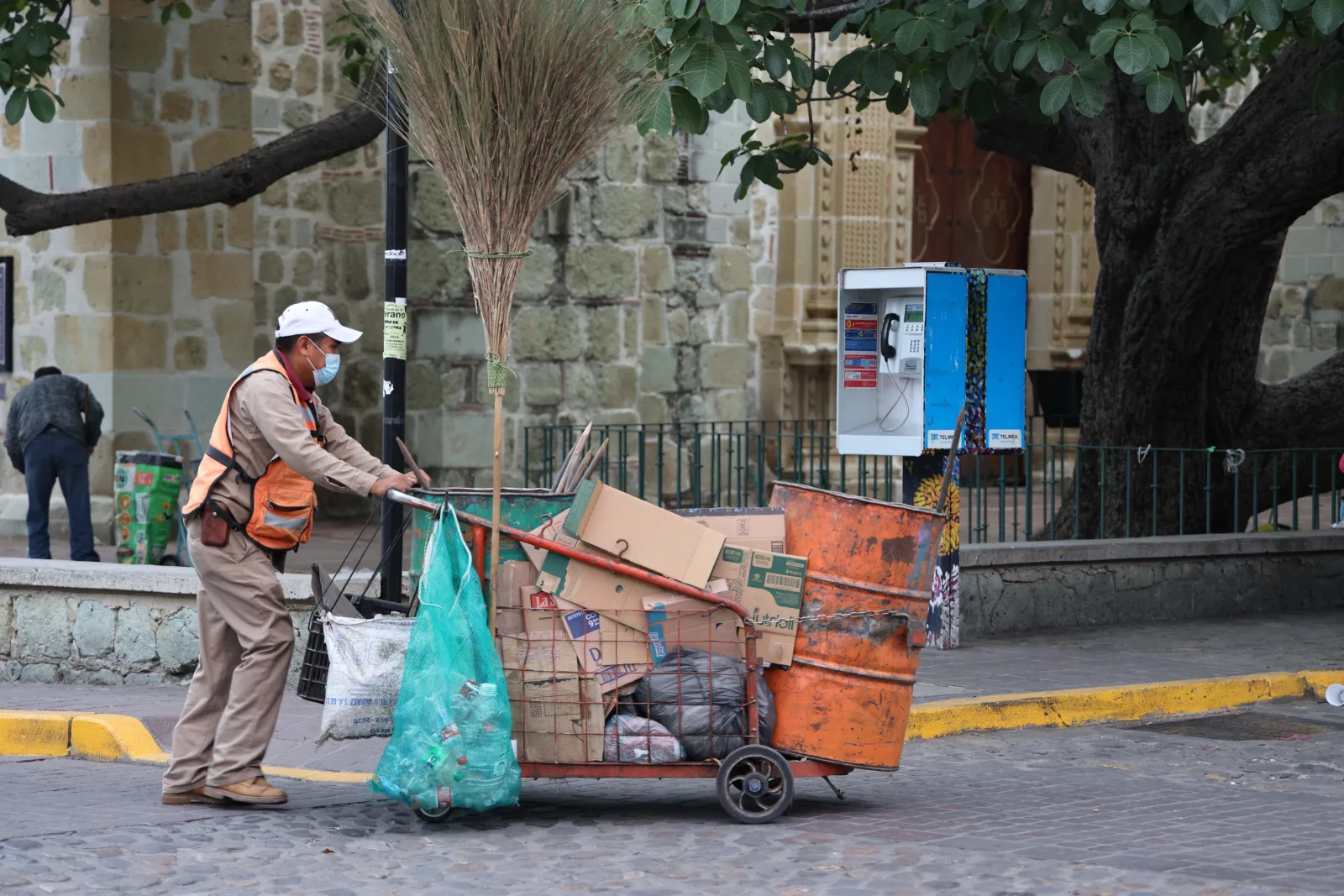 Street cleaner pushing a cart in Oaxaca de Juárez, showcasing urban cleanliness efforts.