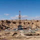 Aerial view of an oil rig amidst desert rock formations, showcasing industrial exploration.