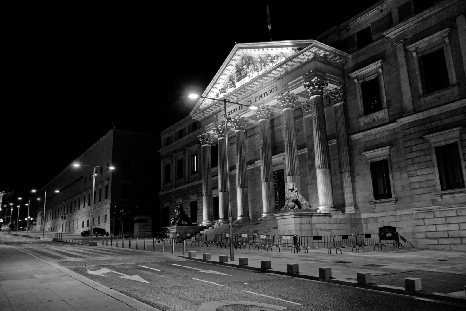 Dramatic black and white image of the Congreso de los Diputados in Madrid at night.