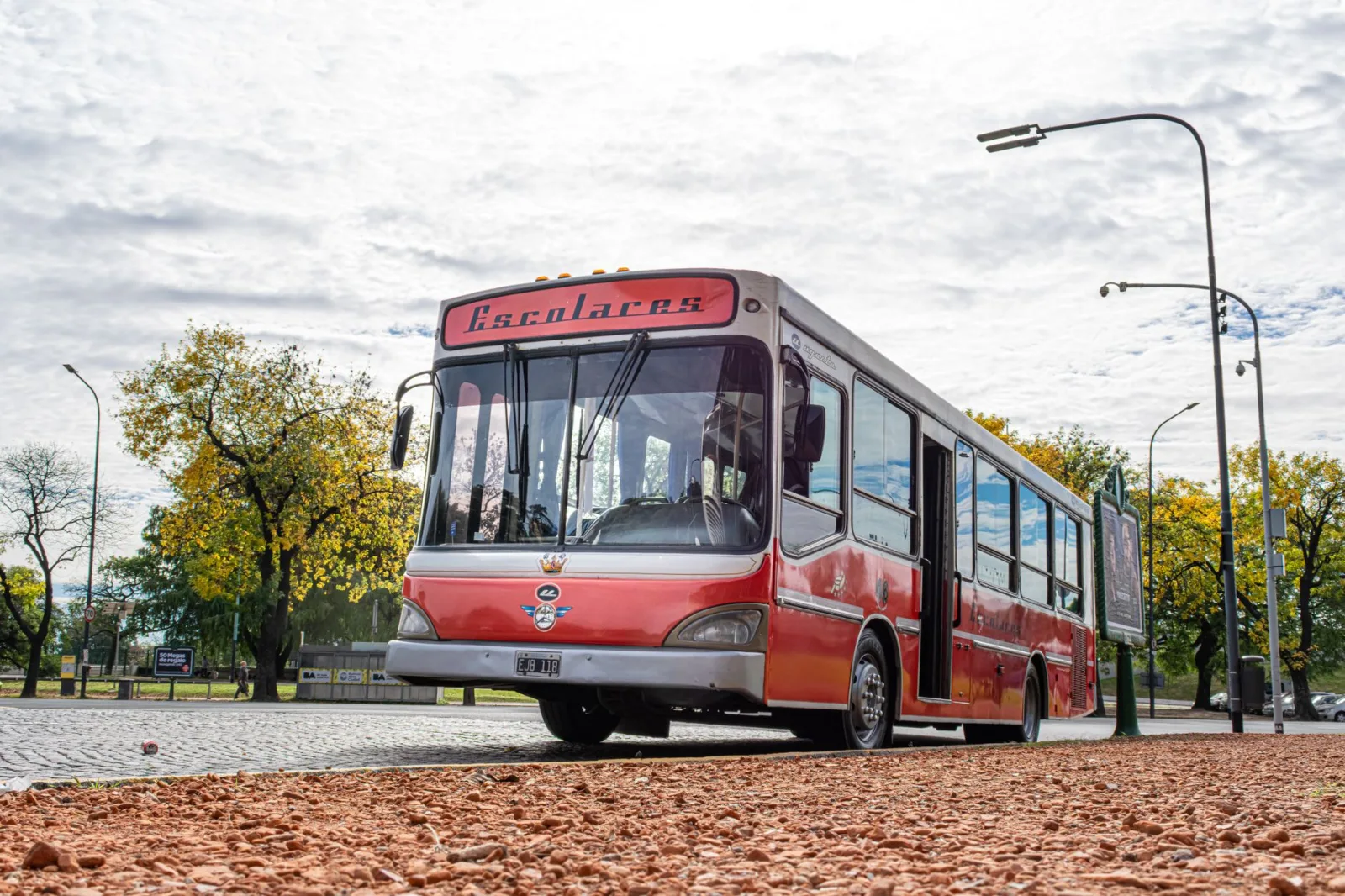 Autobús escolar rojo de estilo antiguo estacionado en una calle de Buenos Aires en un soleado día de otoño.
