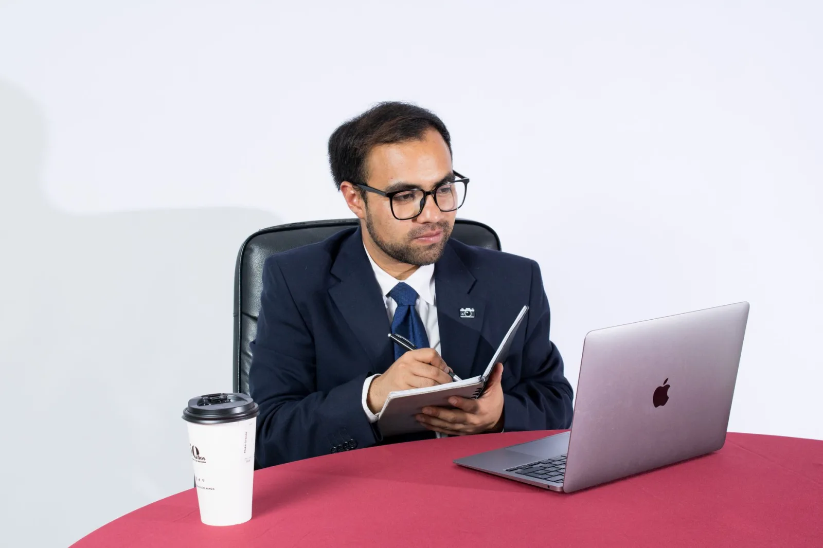 Empresario profesional tomando notas en un escritorio con una laptop y café. Ideal para temáticas de oficina.