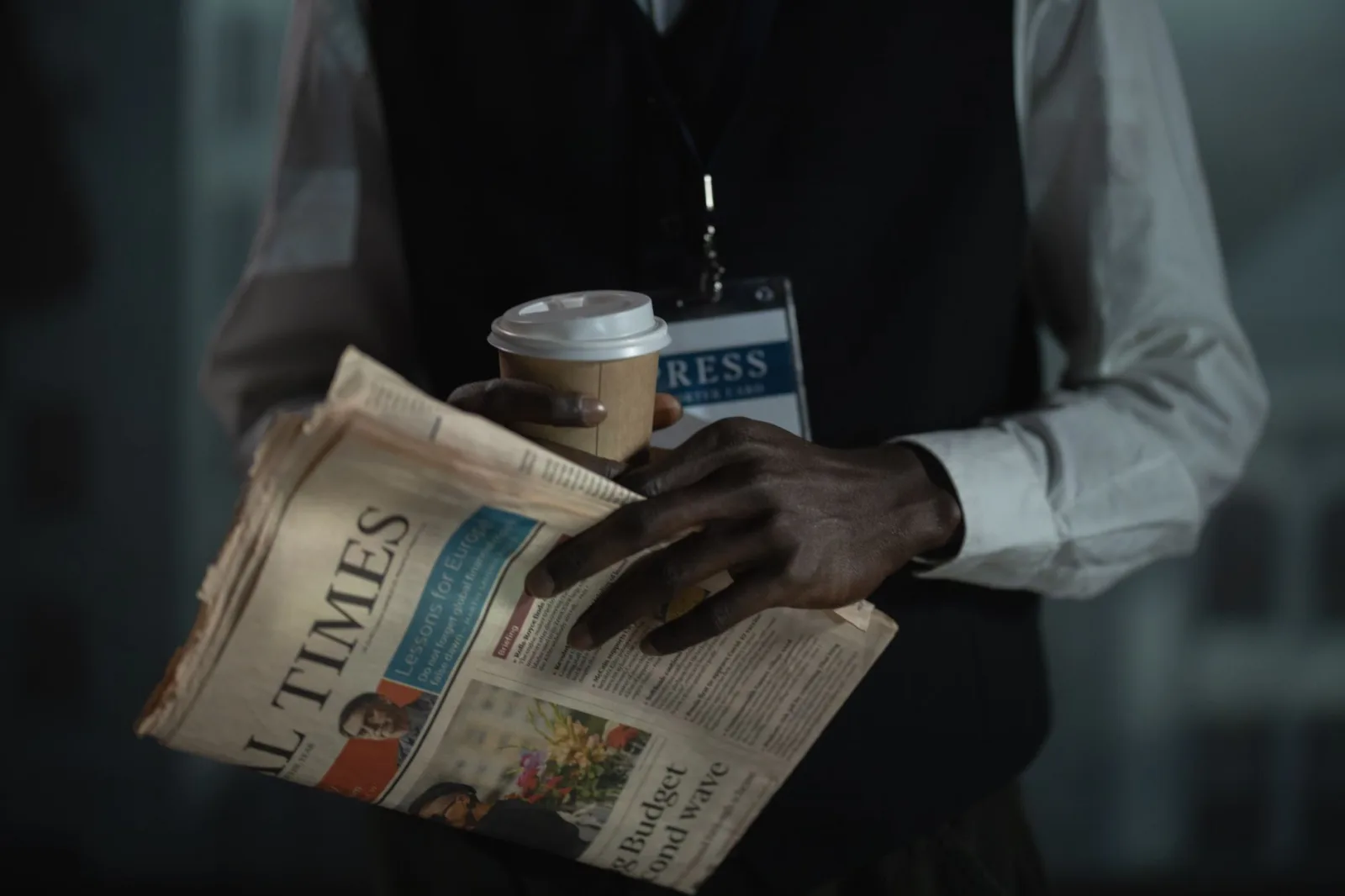 Primer plano de un periodista sosteniendo un periódico y una taza de café, transmitiendo el concepto de prensa y medios.