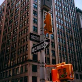 Escena urbana que muestra un rascacielos clásico de Nueva York, semáforos y señales de sentido único.