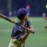 Una impactante escena de acción de una jugadora de sóftbol preparándose para batear bajo el cielo nocturno.