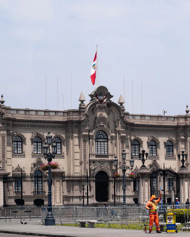 Vista del histórico Palacio de Gobierno en Lima, Perú, con un trabajador en primer plano.