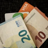 Close-up of euro banknotes and credit cards on a dark textured surface.