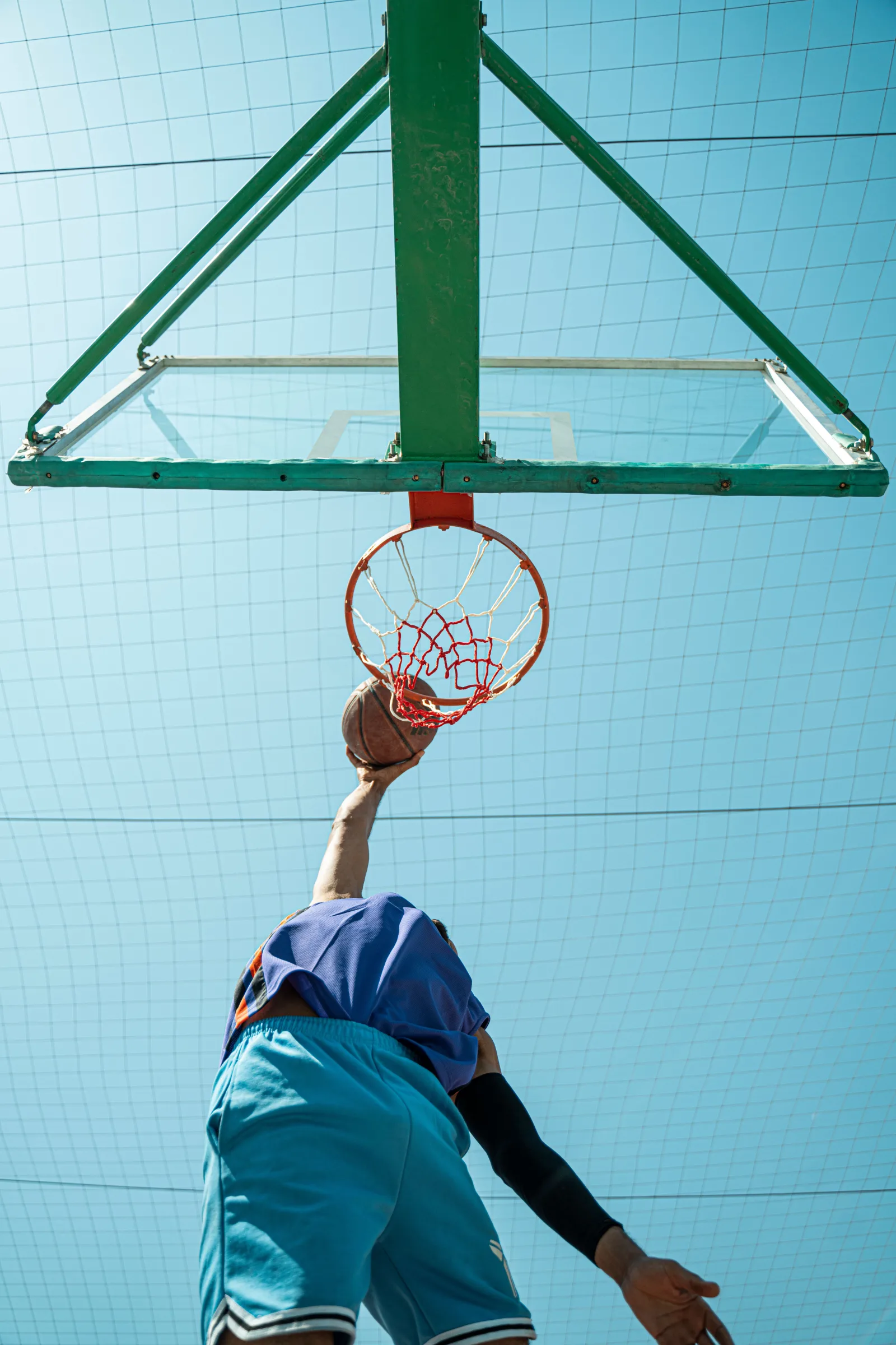Plano dinámico desde un ángulo bajo de un jugador de baloncesto haciendo una clavada al aire libre en Bagdad, Irak.