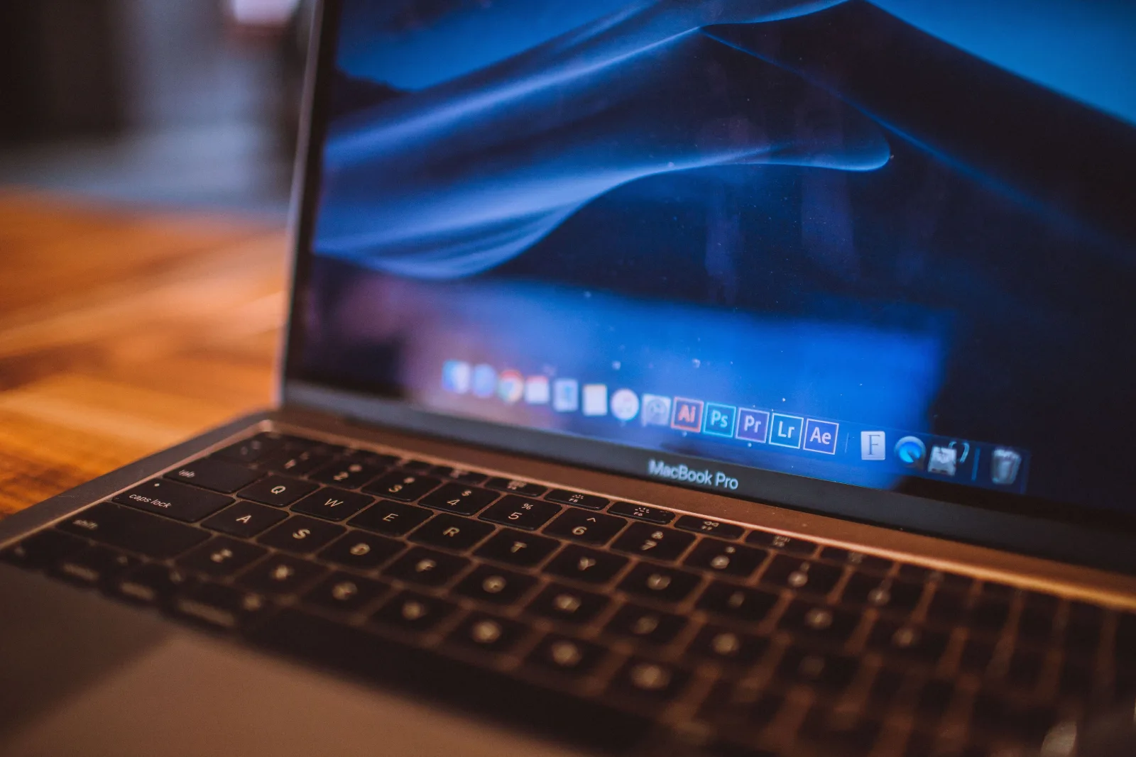 Vista de cerca de un MacBook Pro abierto con la pantalla azul tenue en un acogedor espacio interior.
