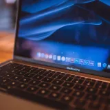 Vista de cerca de un MacBook Pro abierto con la pantalla azul tenue en un acogedor espacio interior.
