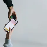 Manos usando un teléfono inteligente y una terminal para realizar un pago sin efectivo, mostrando métodos de transacción modernos.