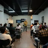 Un profesional dando una conferencia a un grupo en un moderno taller en interiores.