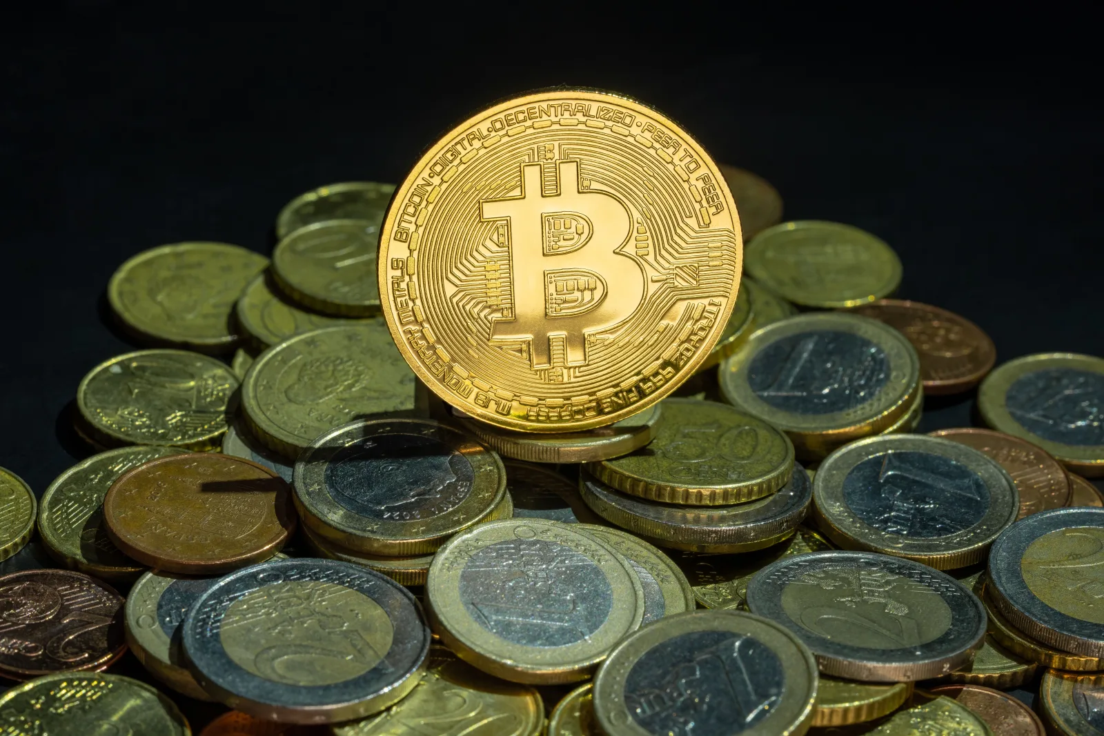Vista cercana de monedas de Bitcoin y euros, simbolizando las finanzas digitales y tradicionales.