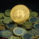 Vista cercana de monedas de Bitcoin y euros, simbolizando las finanzas digitales y tradicionales.