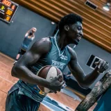 Engaging moment of basketball players during an indoor training session on a wooden court.