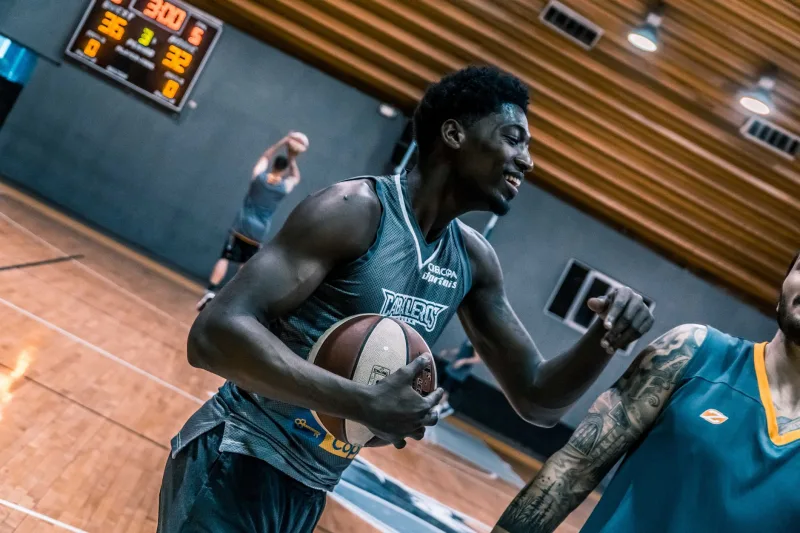 Engaging moment of basketball players during an indoor training session on a wooden court.