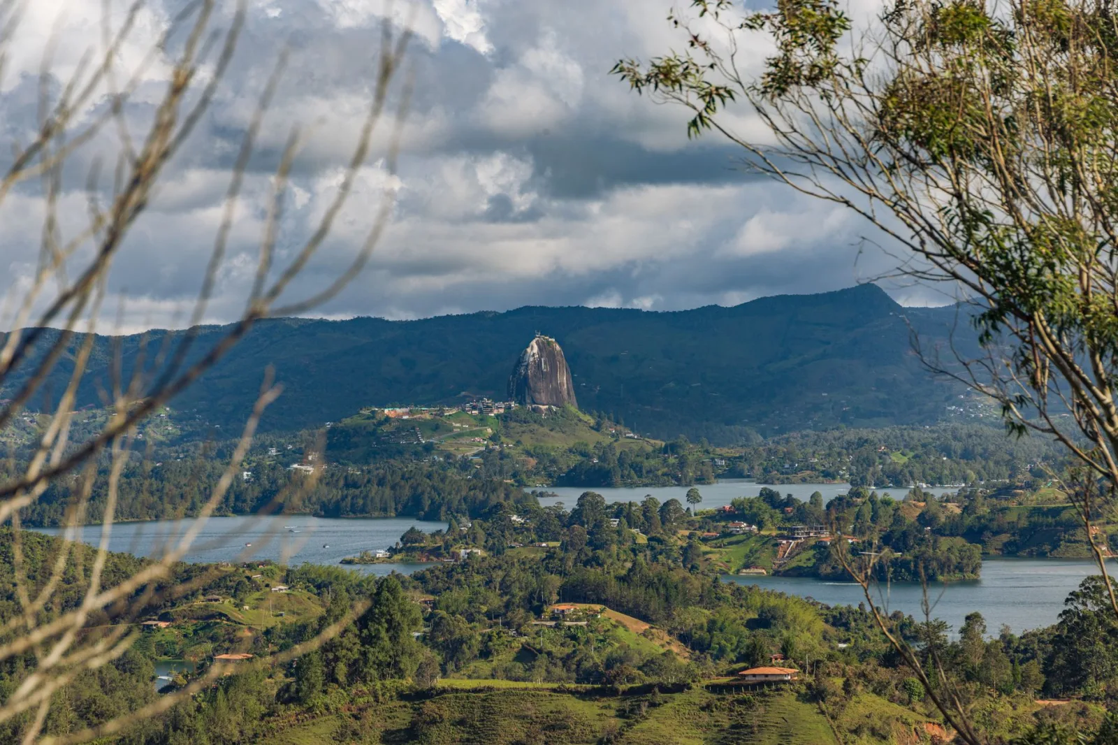 Breathtaking aerial view of El Peñol and lush landscape in Colombia, surrounded by lakes under dramatic skies.